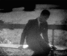 a black and white photo of a man in a suit kneeling down