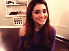 a woman with red hair is smiling and wearing a purple sweater ..