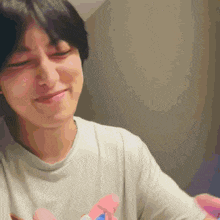 a man in a white shirt is smiling and holding a pink and blue toy .
