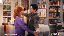a man and woman hugging in a living room with a nbc logo
