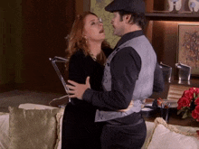 a man and woman are hugging in a living room with a picture on the wall