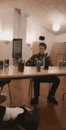 a man sits at a table with a bottle and glasses