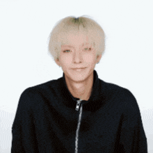 a man with blonde hair is wearing a black jacket and smiling