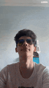 a young man wearing sunglasses and a white shirt with the word luma on the bottom right