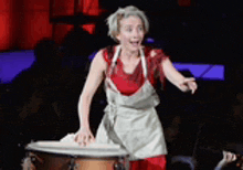 a woman wearing an apron is standing in front of a drum .