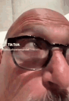 a close up of a man wearing glasses and a nose ring .