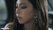 a close up of a woman 's face wearing earrings and a necklace
