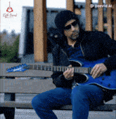 a man is sitting on a bench playing a blue electric guitar