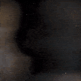 a blurry picture of a man in a suit and tie standing in the dark .