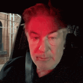a man sitting in a car with a red light shining on his face