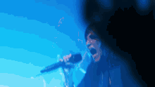 a man singing into a microphone with a blue background