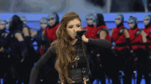 a woman is singing into a microphone in front of a crowd