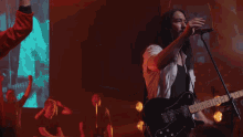 a group of people standing in front of a large screen with a picture of a man playing a guitar