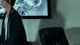a man in a black robe stands in front of a large screen