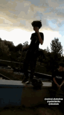 a man wearing a miav shirt is standing on a ledge