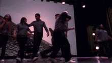 a group of people are dancing on a stage and one of them is wearing a shirt that says ' prisoners ' on it