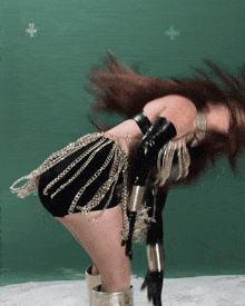 a woman in a black and gold outfit with chains on her skirt