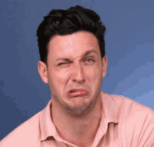 a man in a pink shirt makes a sad face