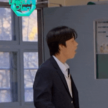 a man in a suit and tie is standing in front of a door with the words debut plan on it .
