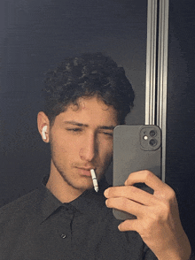a young man is taking a selfie with his phone and a cigarette in his mouth