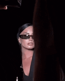 a close up of a woman wearing sunglasses and a black dress .