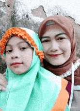 a woman and a little girl are posing for a picture and the woman is wearing a green hijab