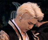 a close up of a man with blonde hair wearing a kimono and earbuds .