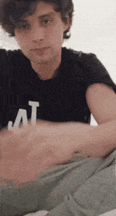 a young man wearing a black t-shirt with the letter t on it