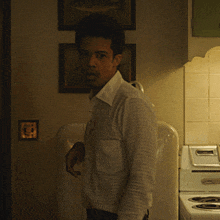 a man in a white shirt stands in front of a stove with a sticker on it that says ' stove '