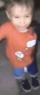 a blurry picture of a child wearing an orange shirt with a sheep on it