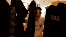 a man wearing sunglasses holds up a black shirt with the letter jrr on it