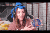 a woman wearing headphones and a blue hat is holding a cd of sonic the hedgehog .