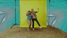 a man and a woman are posing for a picture in front of a yellow backdrop