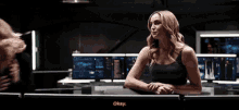 a woman in a black tank top says okay in front of a computer screen