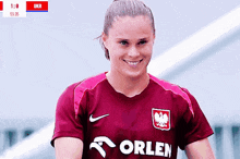 a woman wearing a maroon orlen shirt smiles