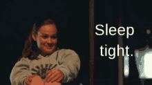 a girl in a sweatshirt is holding another girl 's leg and the words sleep tight are behind her
