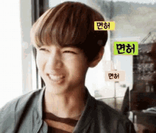 a young man with korean writing on his head smiles