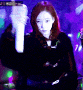 a woman in a black coat is holding a white object in a dark room