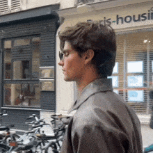 a man in a leather jacket is walking down a street in front of a building that says paris-housing .