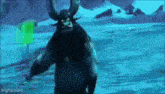 a man with horns and a beard is standing in the water .