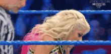 a woman in a wrestling ring with a referee behind her .