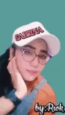 a woman wearing glasses and a baseball cap with the name sabrina written on it .