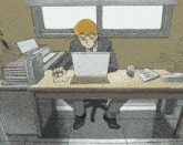 a man sits at a desk using a laptop