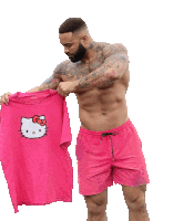a shirtless man is holding a pink hello kitty t-shirt