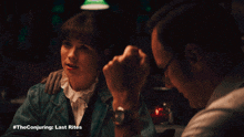 a man and a woman are sitting at a table with the conjuring last rites written on the bottom