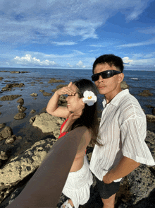 a man and a woman taking a selfie on a rocky beach