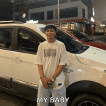 a man standing in front of a white car that says " my baby " on it