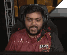 a man wearing headphones and a renegades shirt looks at the camera