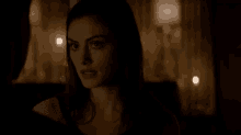 a close up of a woman 's face in a dark room with candles in the background