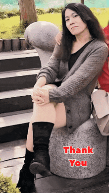 a woman sits on a rock with the words thank you written on it
